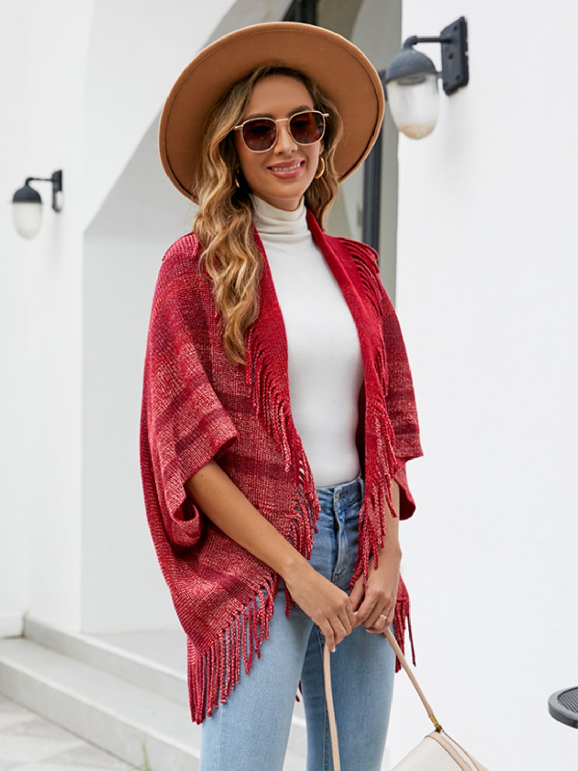 Red fringed poncho shown from the front with the model's hands together.