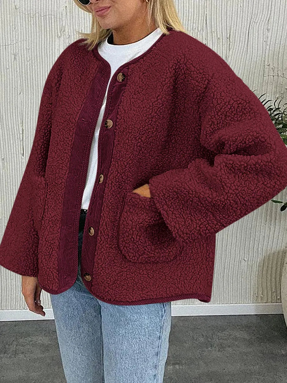 Burgundy textured jacket worn with a white T-shirt and jeans, with one hand in a pocket.