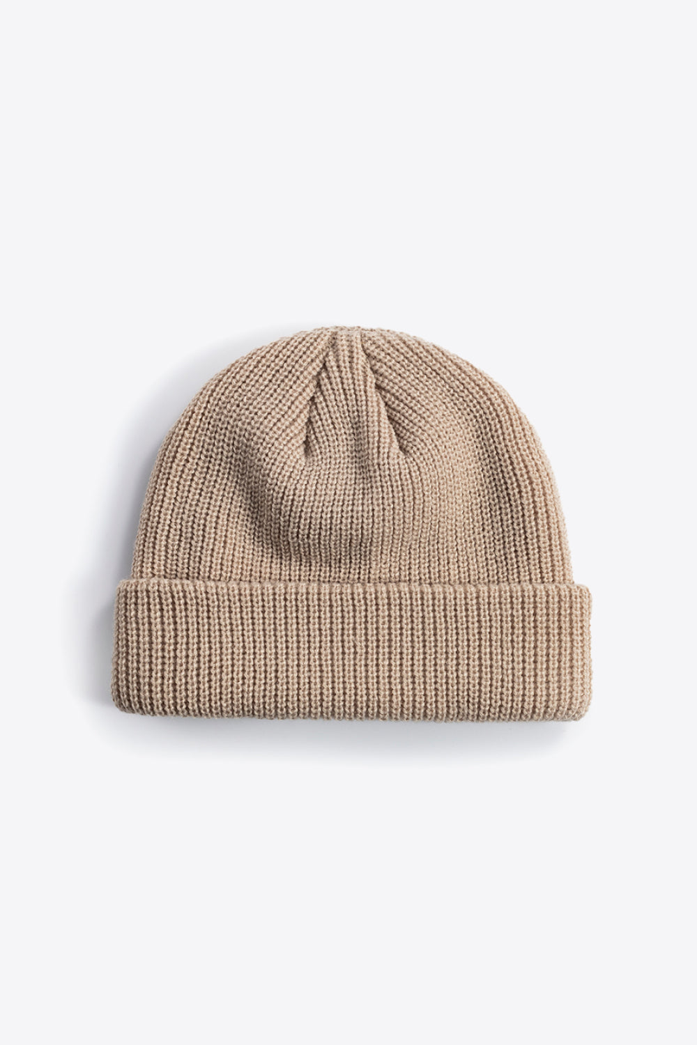 Tan knit beanie laid flat, showing its folded cuff and shaped crown.