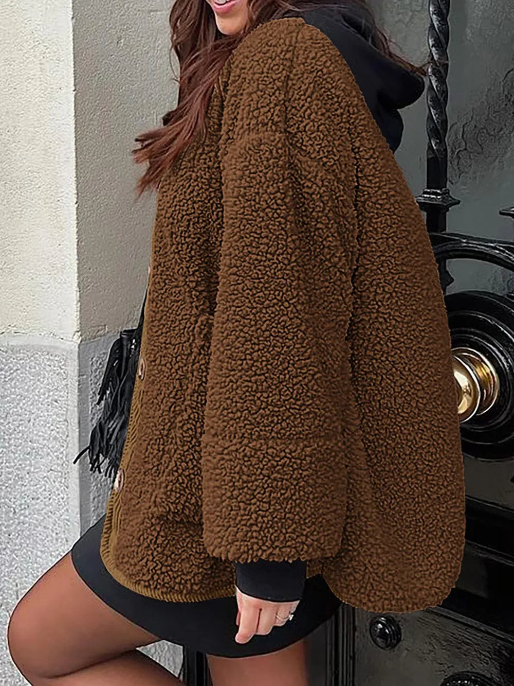 Rear three-quarter view of the brown textured jacket worn over a black hooded layer.