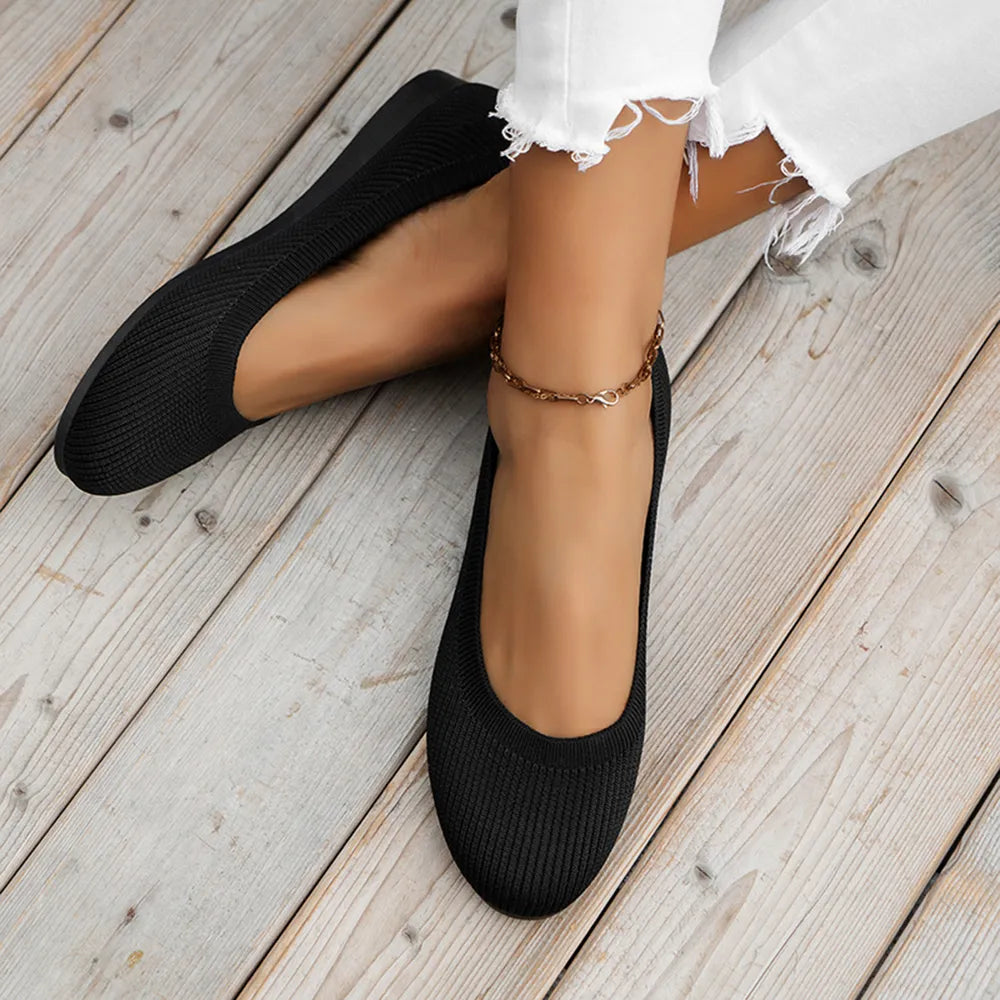 Black knit ballet flats worn with white cropped pants.