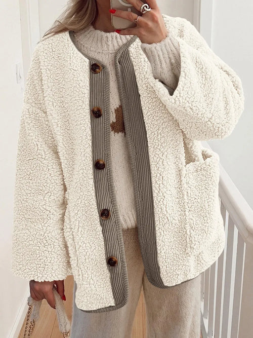 Cream textured jacket with contrast trim and a button front, worn over a cream sweater.