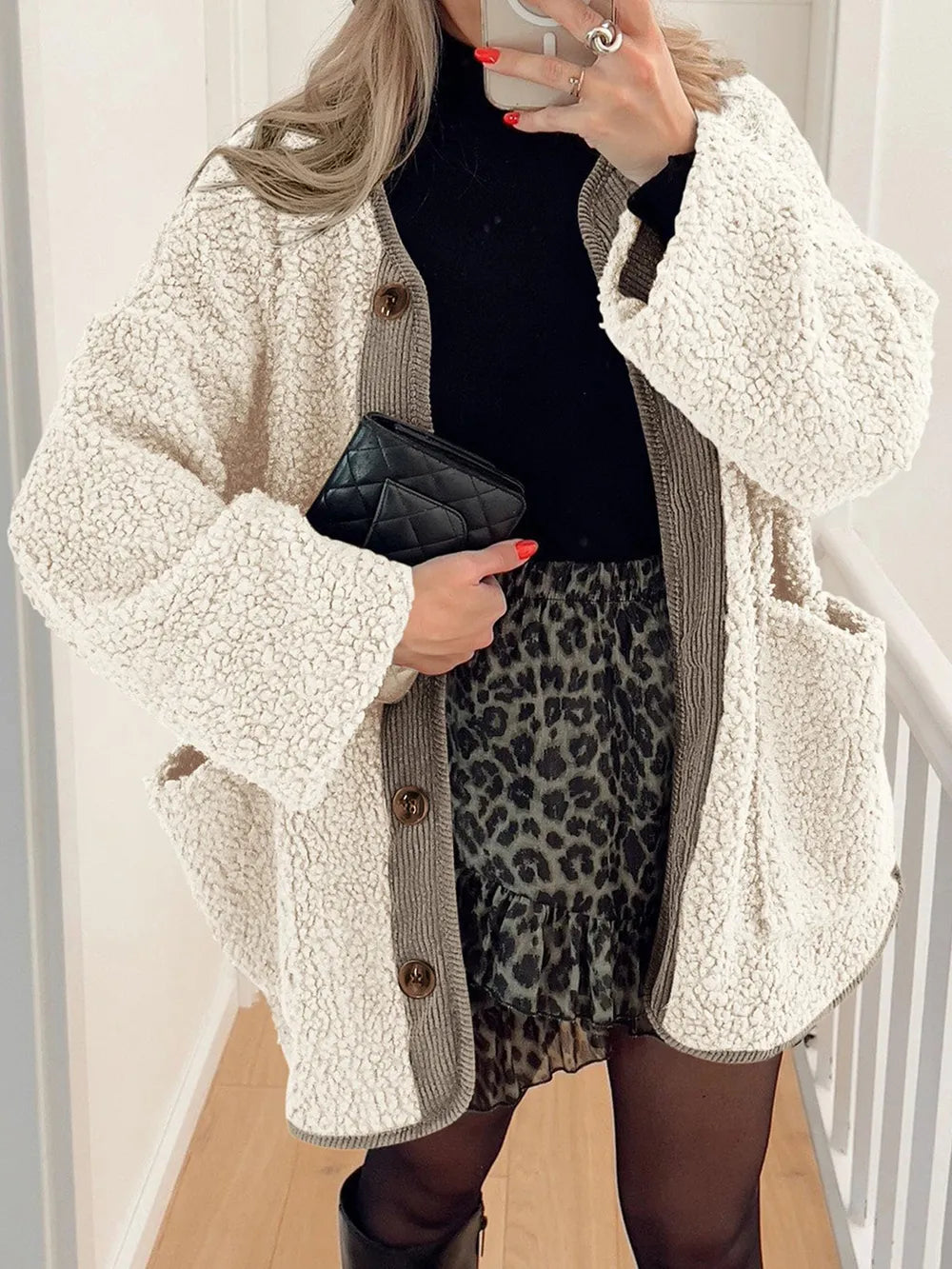 Cream textured jacket worn open over a black top and leopard-print skirt.