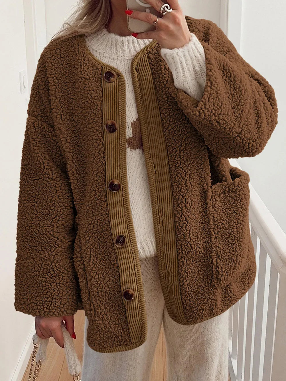 Brown textured jacket with contrast trim, worn over a cream sweater.