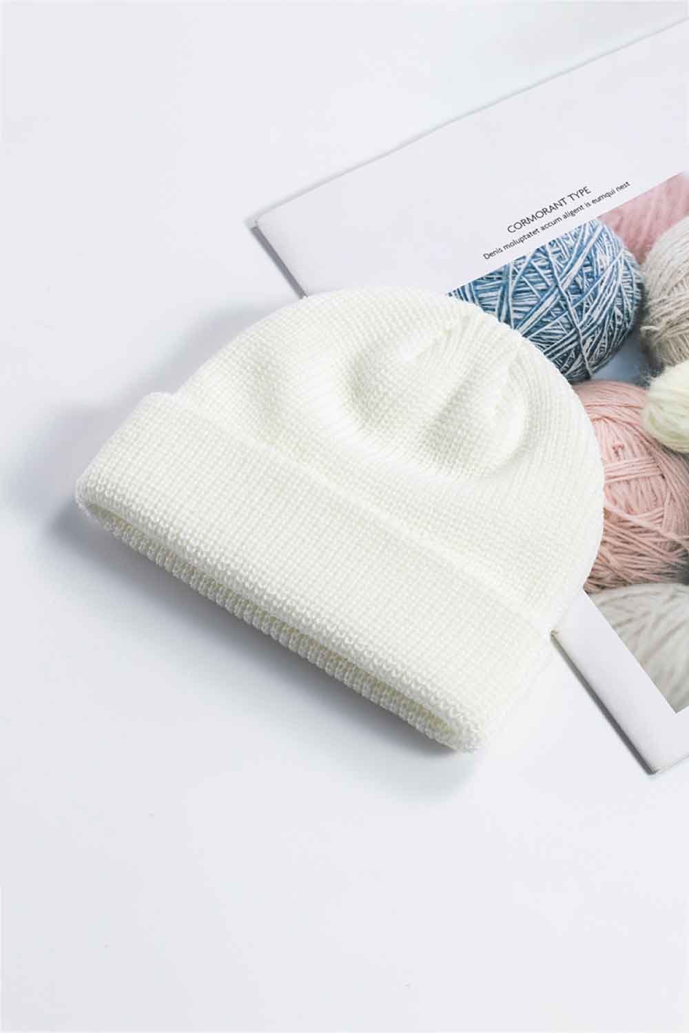 White knit cuff beanie displayed at an angle on a printed page.