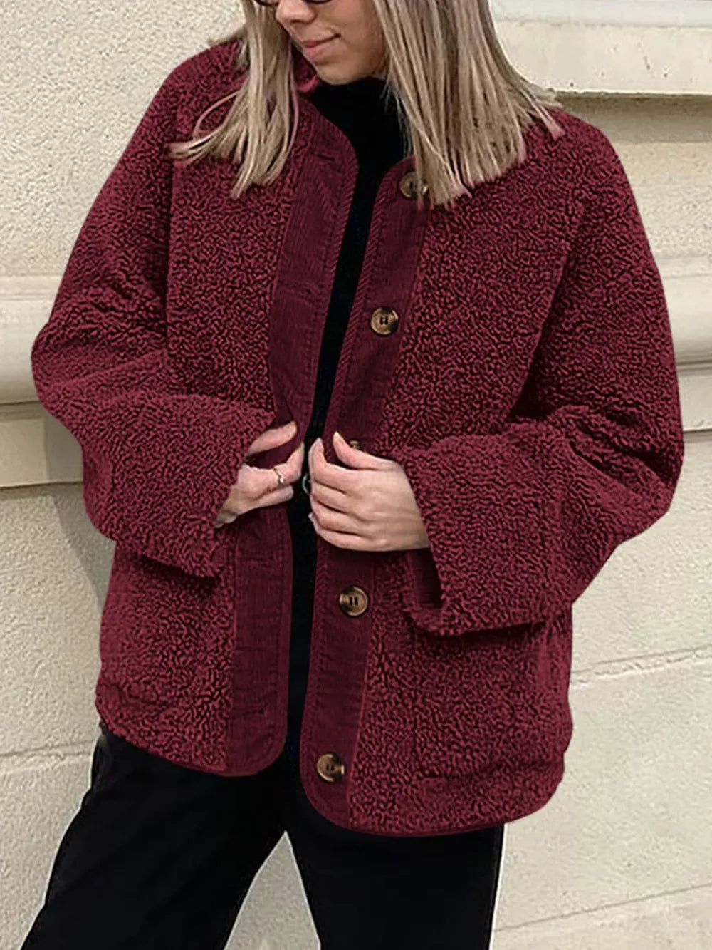 Burgundy textured jacket held open over a black top and trousers.