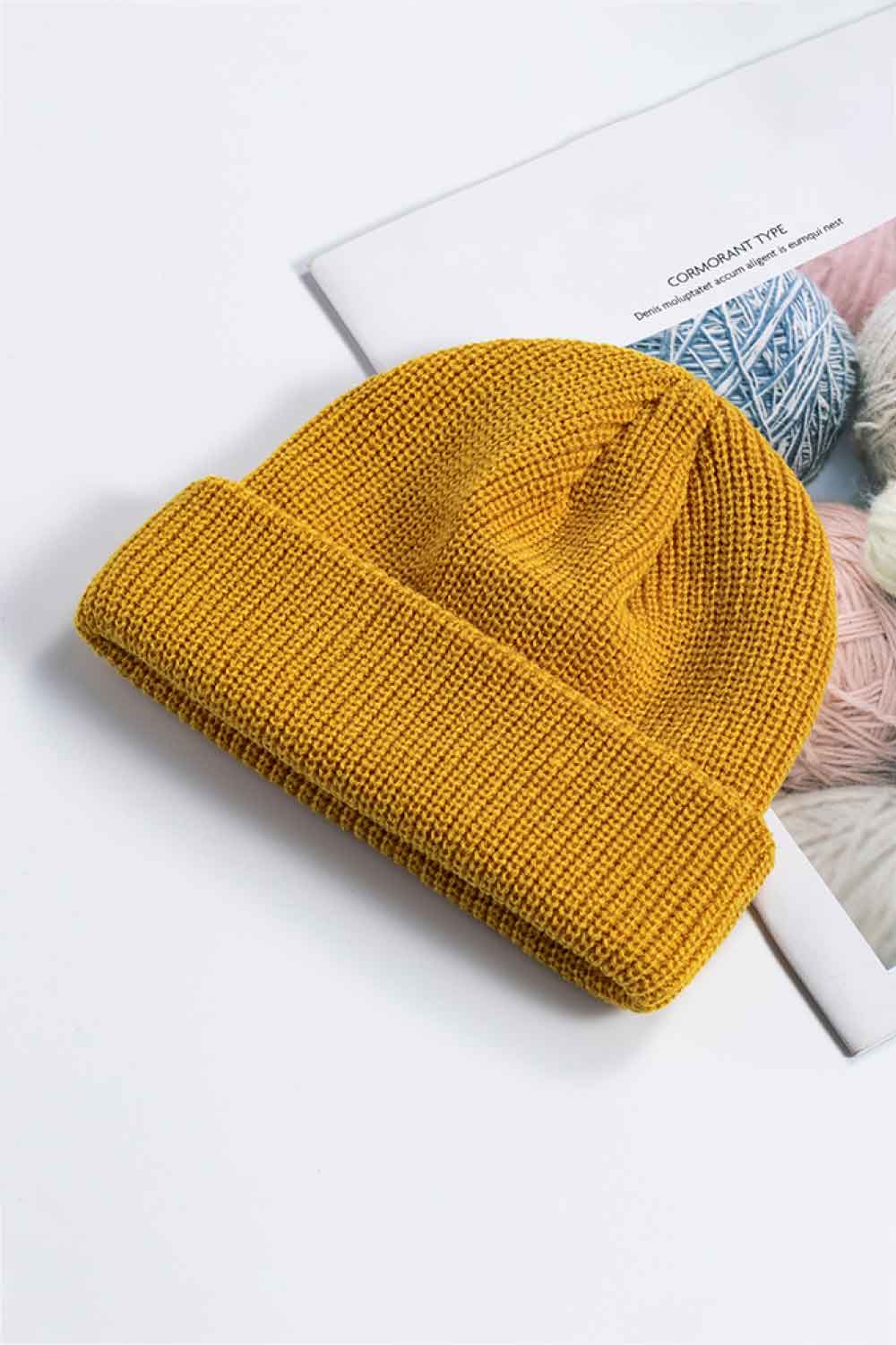 Black knit beanie shown with its cuff folded up.