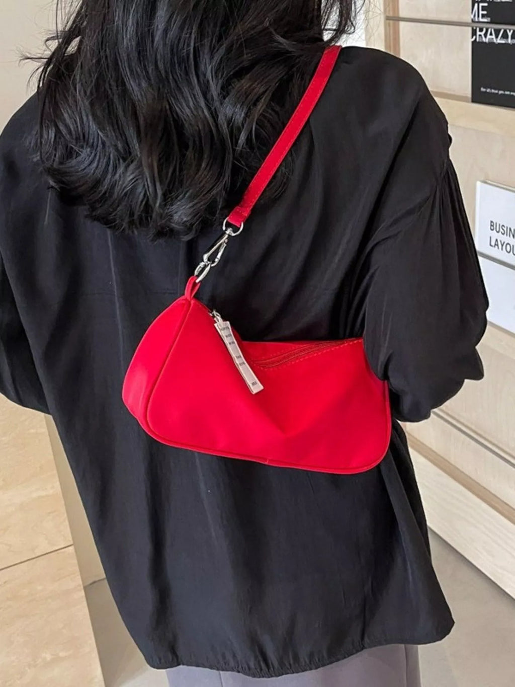 Red bag worn across the back, with its strap running diagonally over a black top.