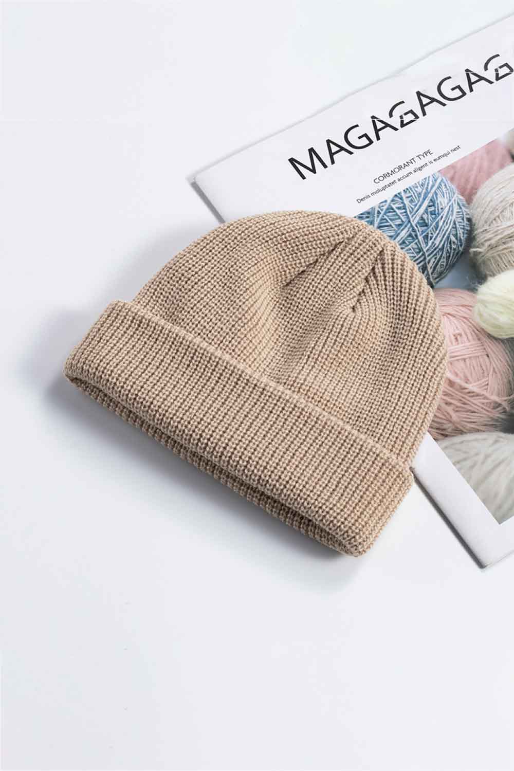 Tan knit cuff beanie displayed at an angle on a printed page.