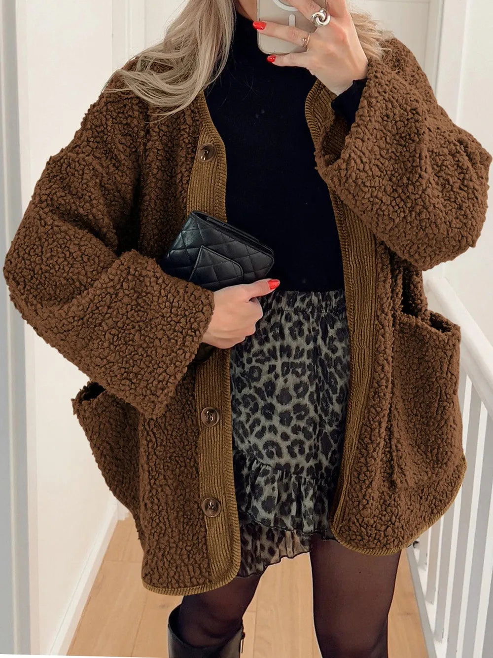 Brown textured jacket worn open over a black top and leopard-print skirt.