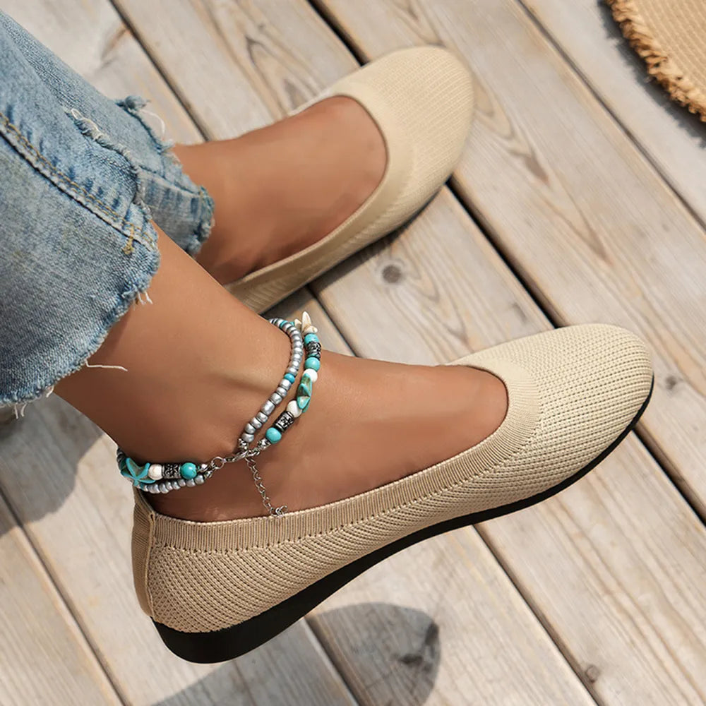 Ivory knit ballet flats worn with cropped jeans.
