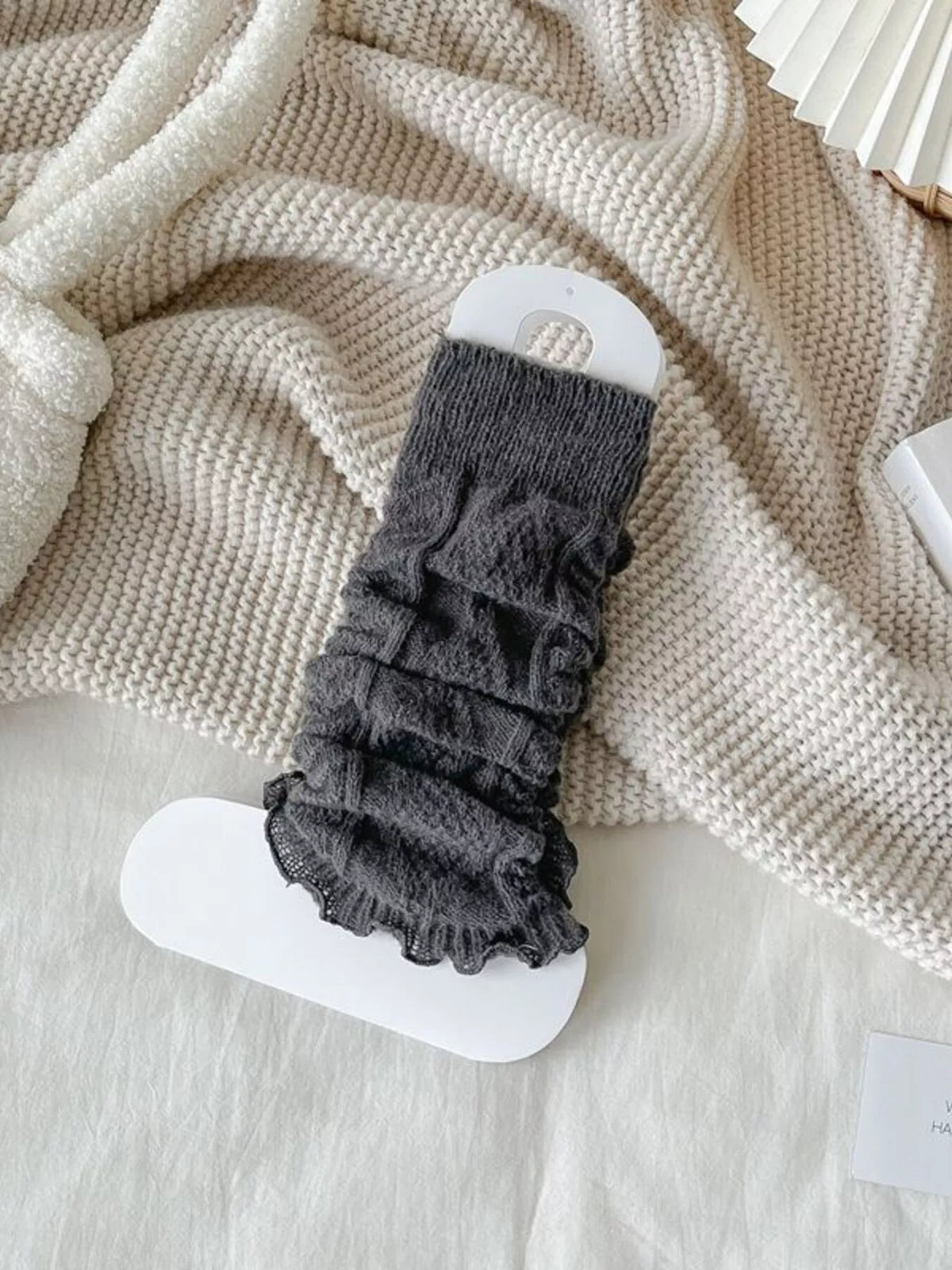 Carbon gray cable-knit leg warmers gathered on a white display card.