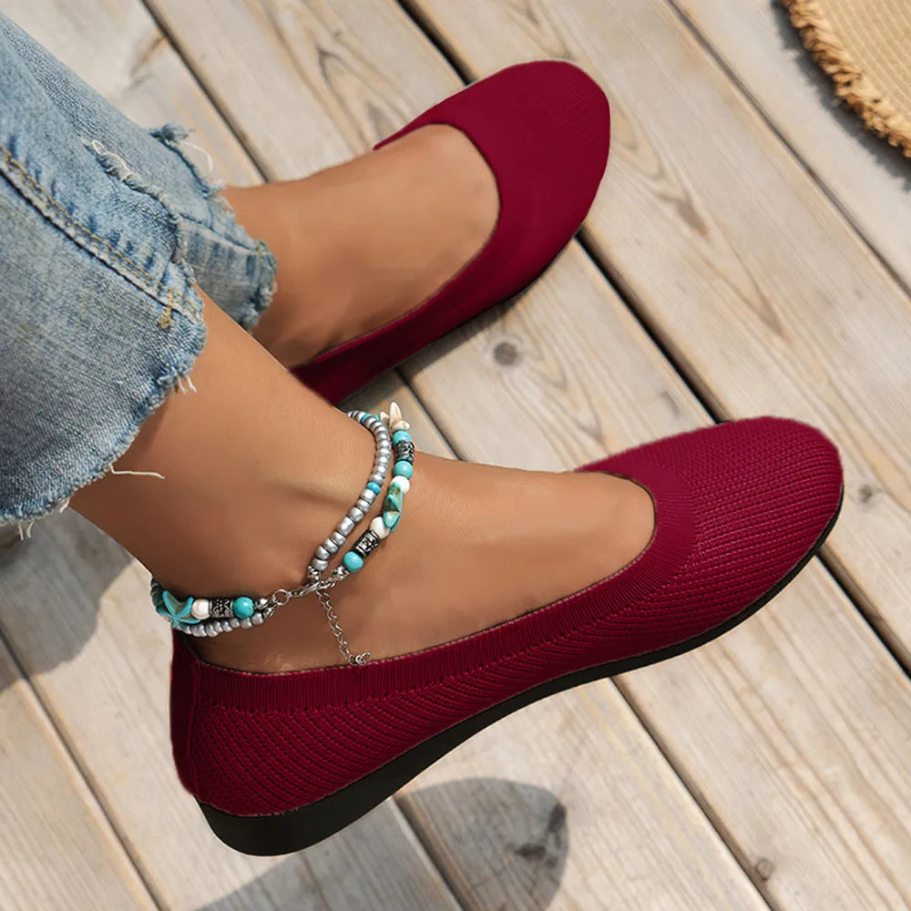 Burgundy knit ballet flats worn with cropped jeans.