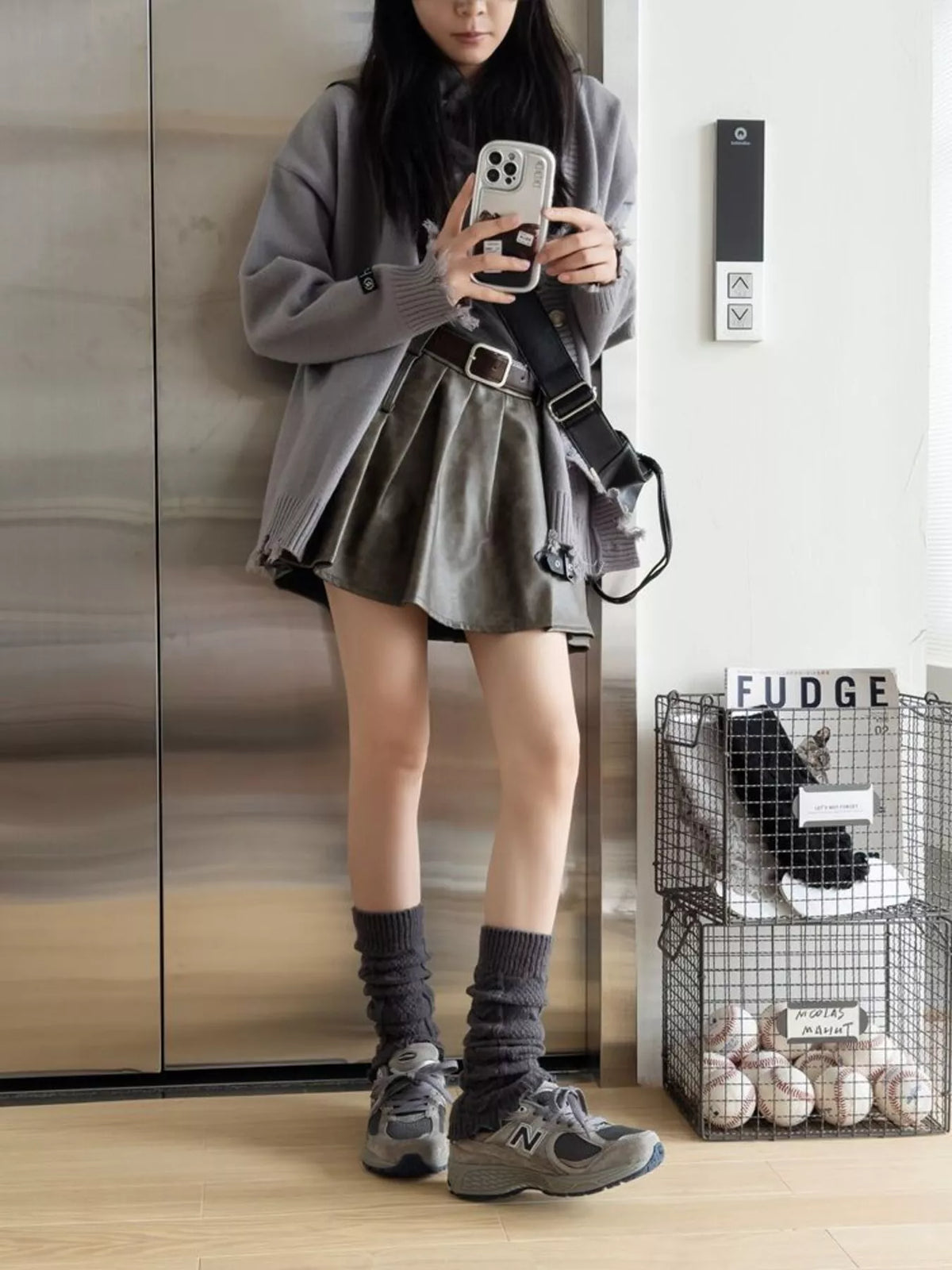 Carbon gray leg warmers worn with gray sneakers and a short black skirt.