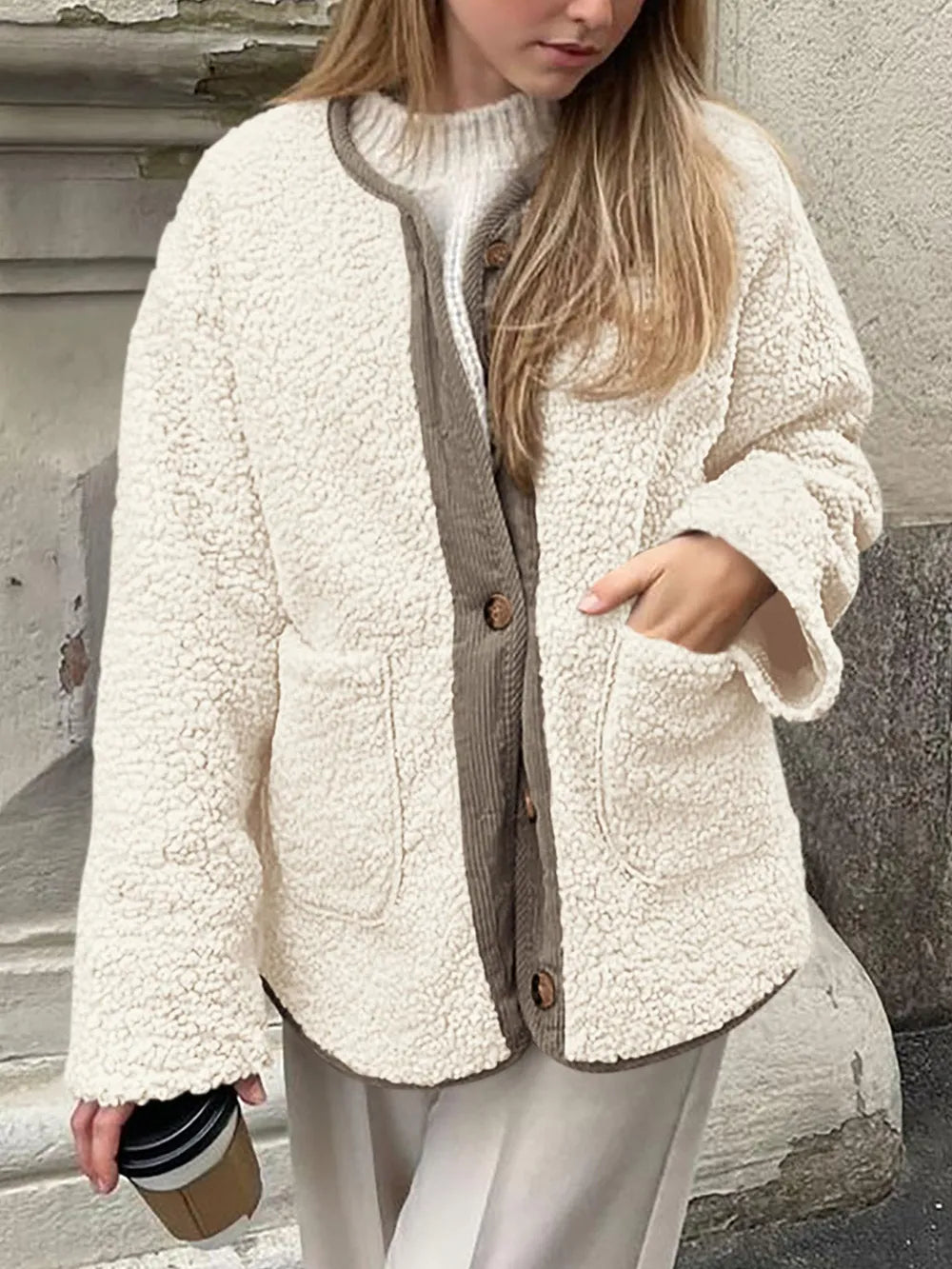 Front view of the cream textured jacket outdoors, with one hand in a patch pocket.