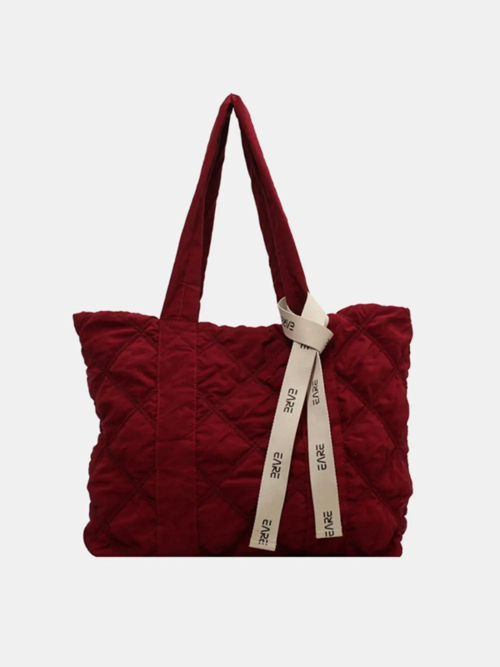 Burgundy quilted tote with long handles and a cream ribbon against a plain background.