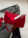 Red zip-top crossbody bag held against gray fabric, showing its short strap and metal clasps.