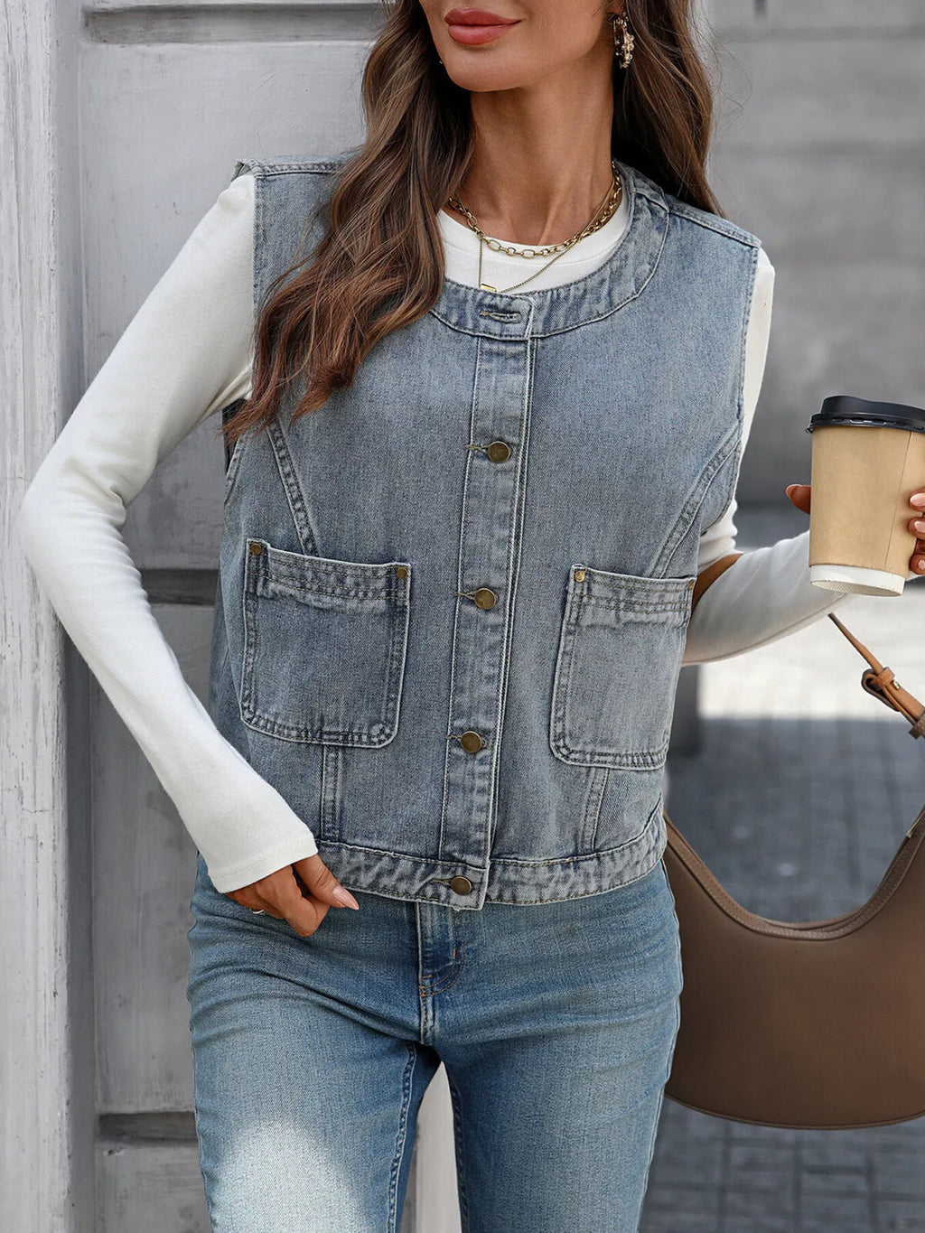 Light-blue denim-look vest buttoned over a white top, shown with a coffee cup and brown bag.