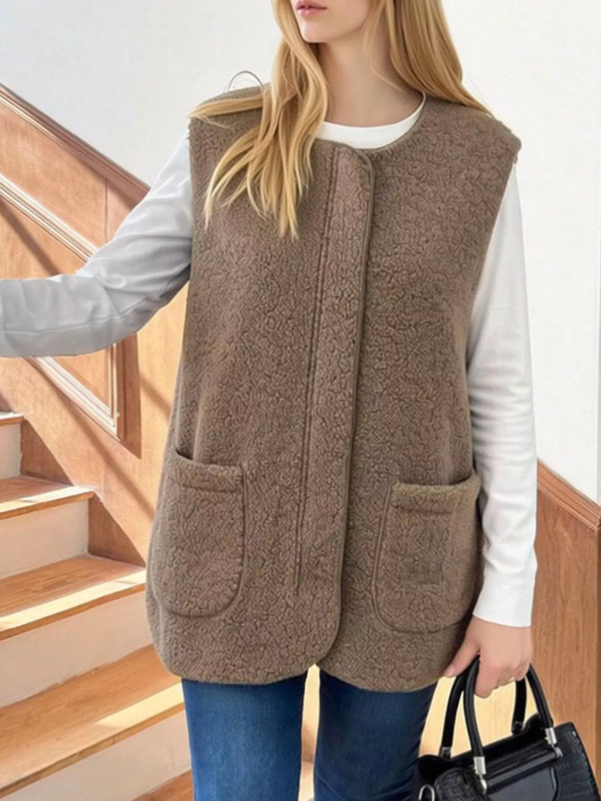 Khaki sherpa vest with two patch pockets, worn over a white shirt with jeans.