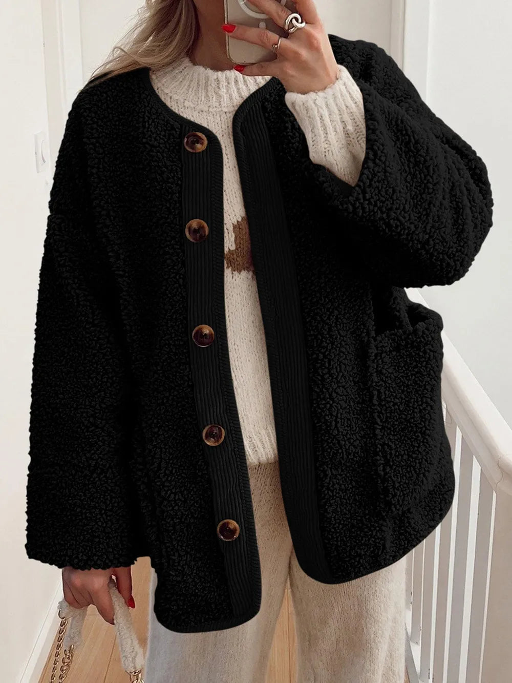 Black textured jacket with contrast trim, worn over a cream sweater.