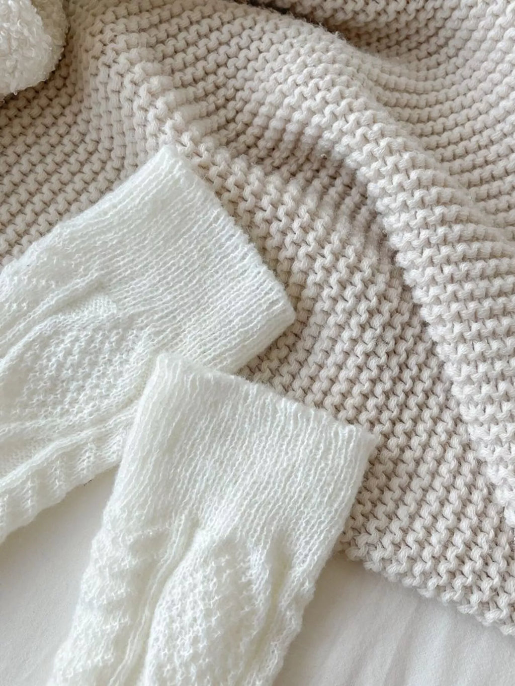 Close-up of the white leg warmers showing ribbed cuffs and cable-knit texture.