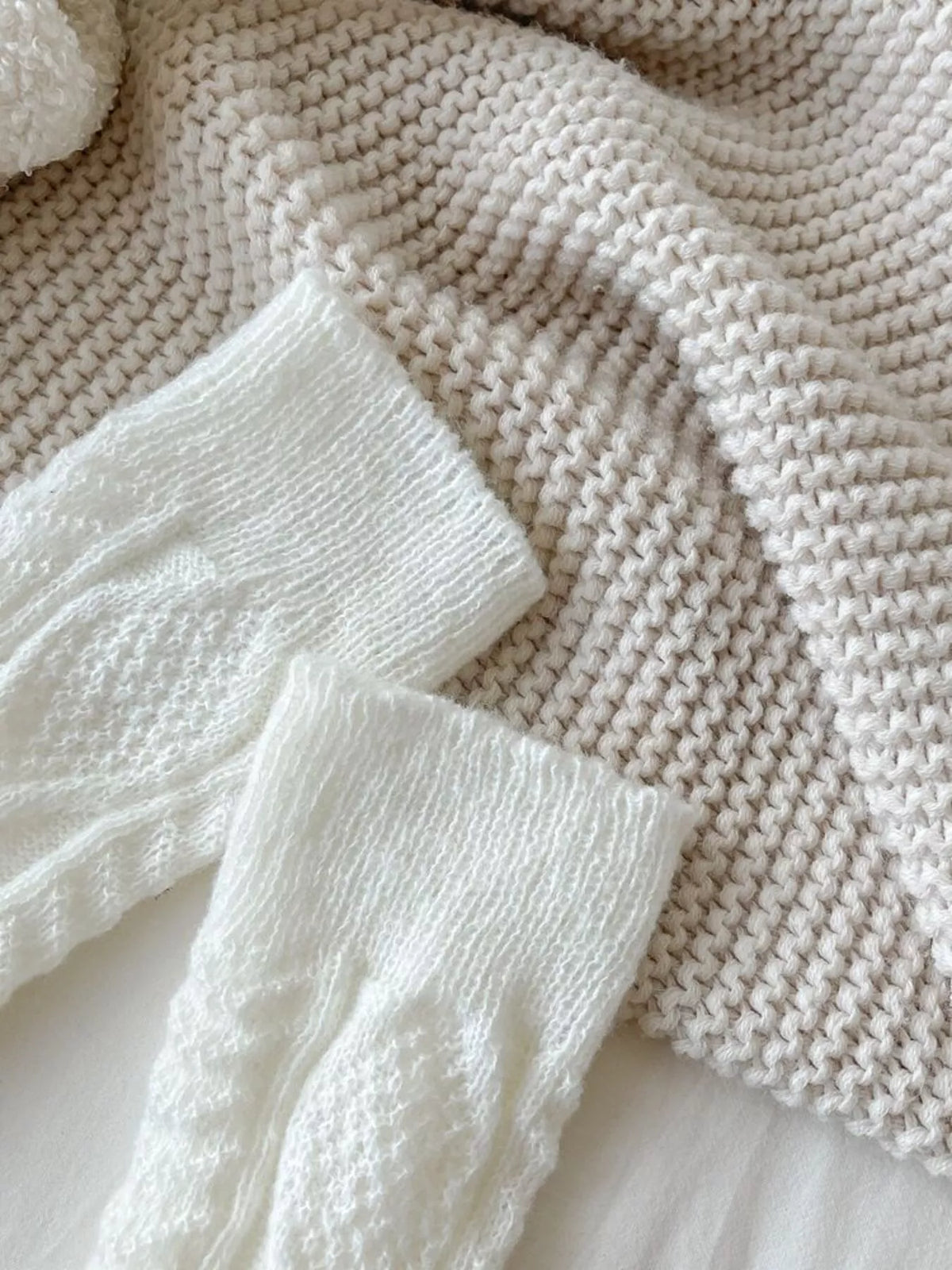 Close-up of the white leg warmers showing ribbed cuffs and cable-knit texture.