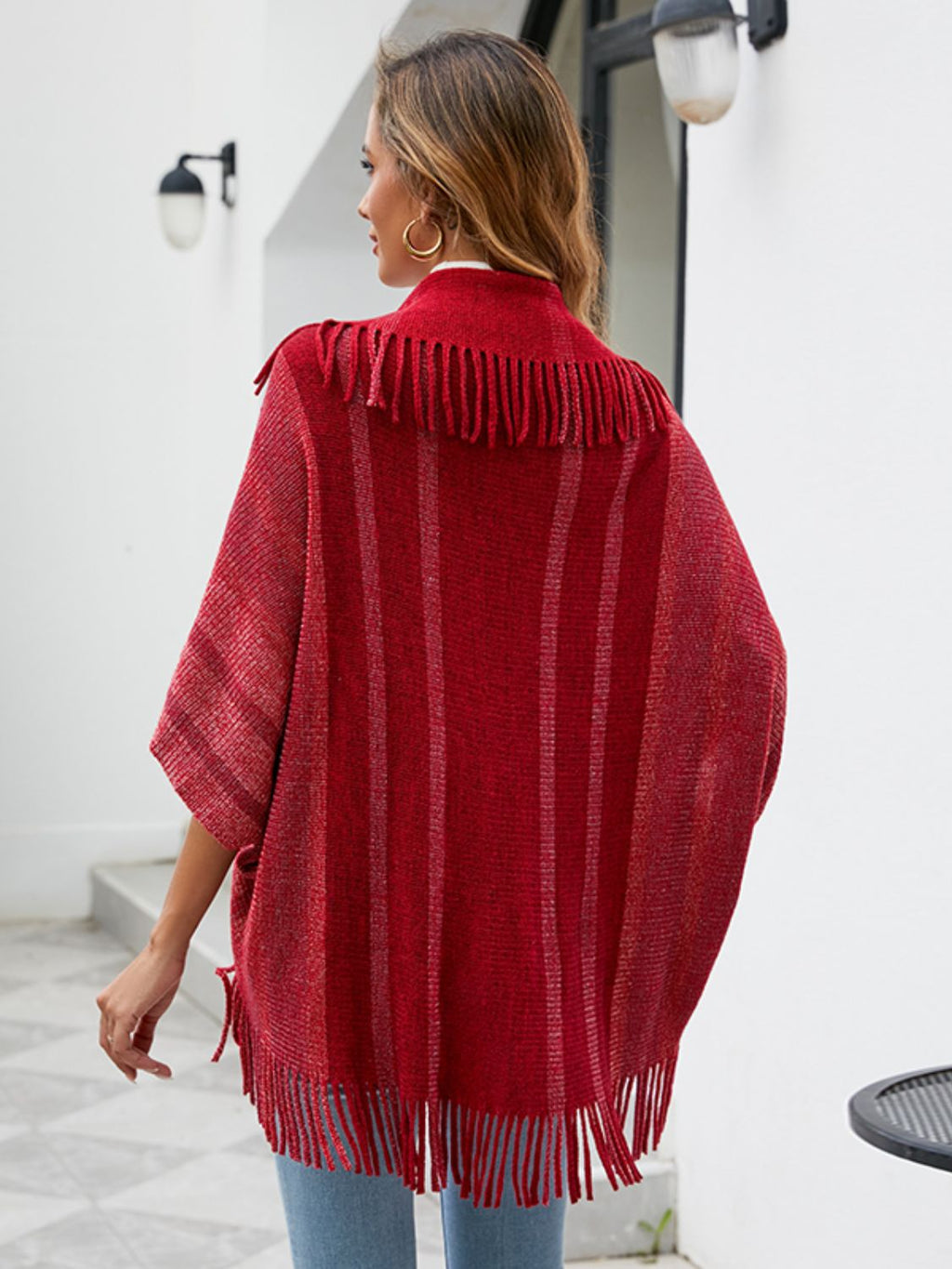 Back view of the red poncho showing fringe across the shoulders and lower hem.