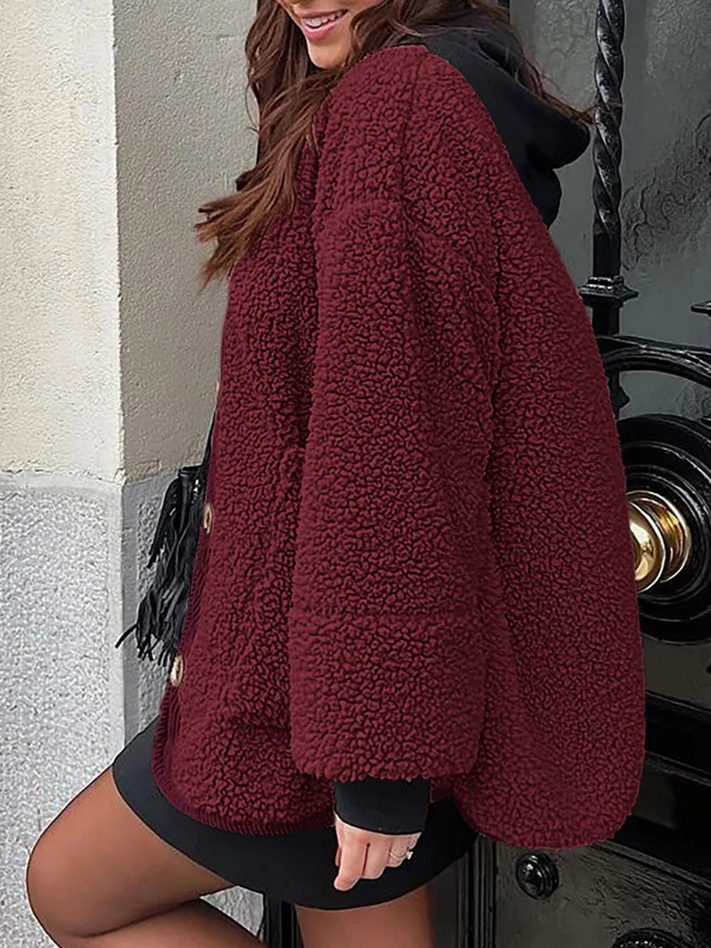 Rear three-quarter view of the burgundy textured jacket worn over a black hooded layer.