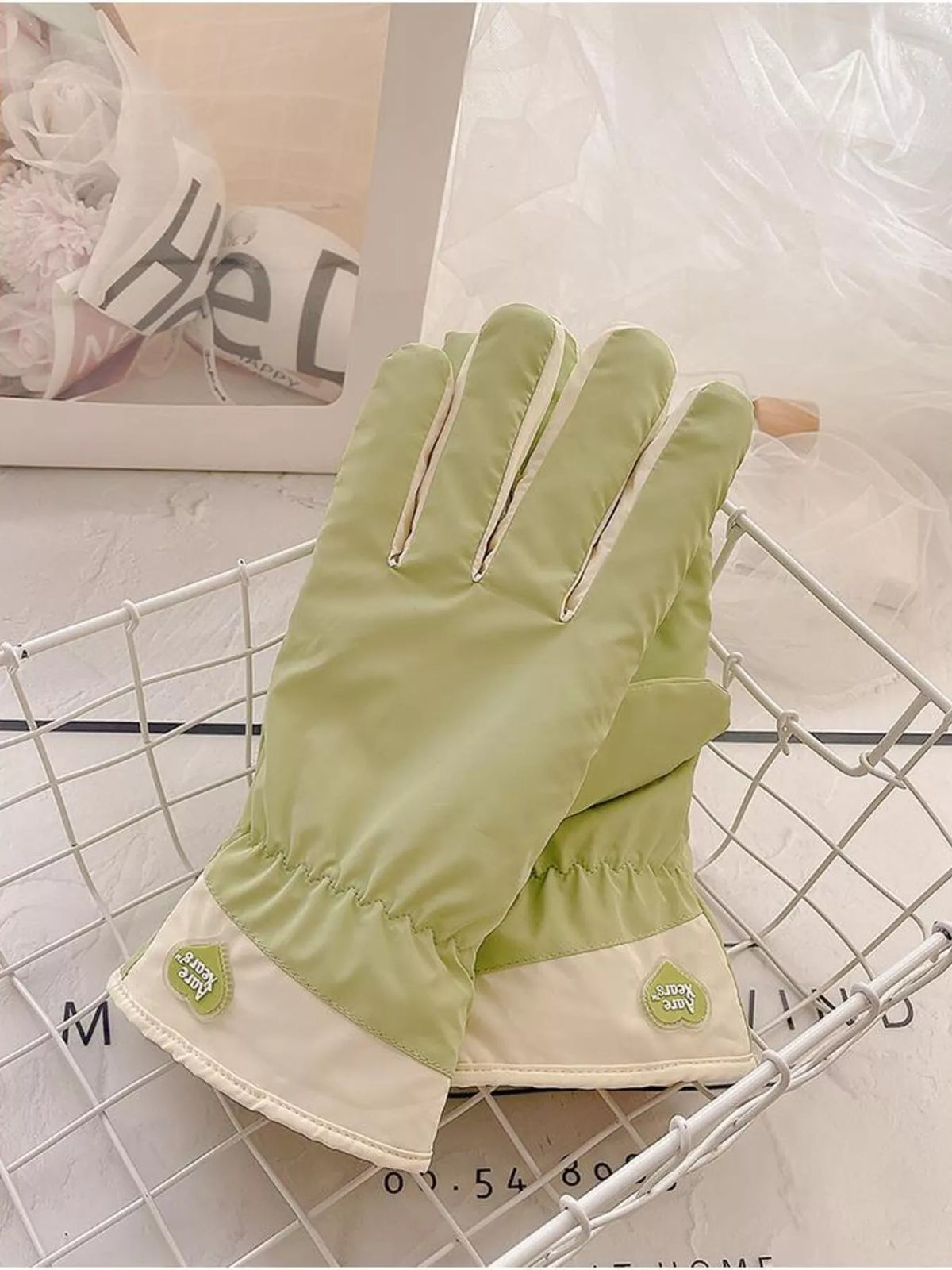 Light green gloves laid diagonally on a wire tray with the cuffs visible.