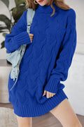 Blue cable-knit turtleneck mini sweater dress shown from the front with a shoulder bag.