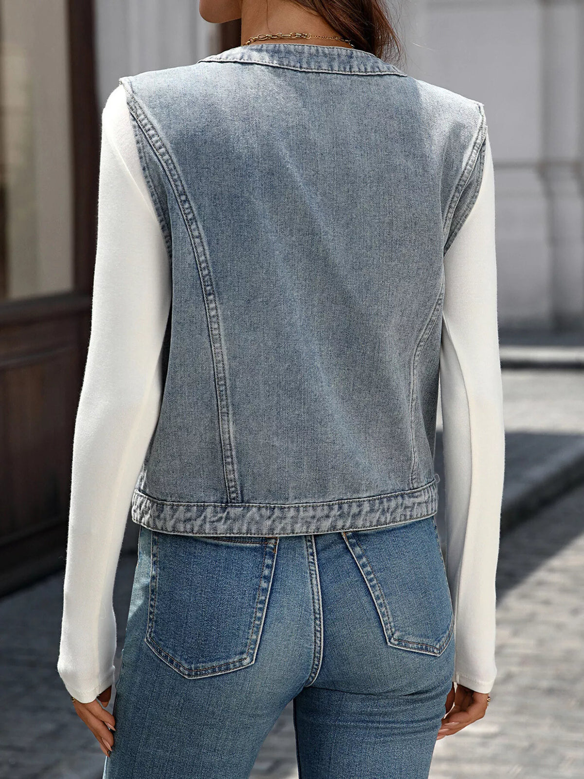 Back view of the light-blue sleeveless vest showing its straight hem and center seam.