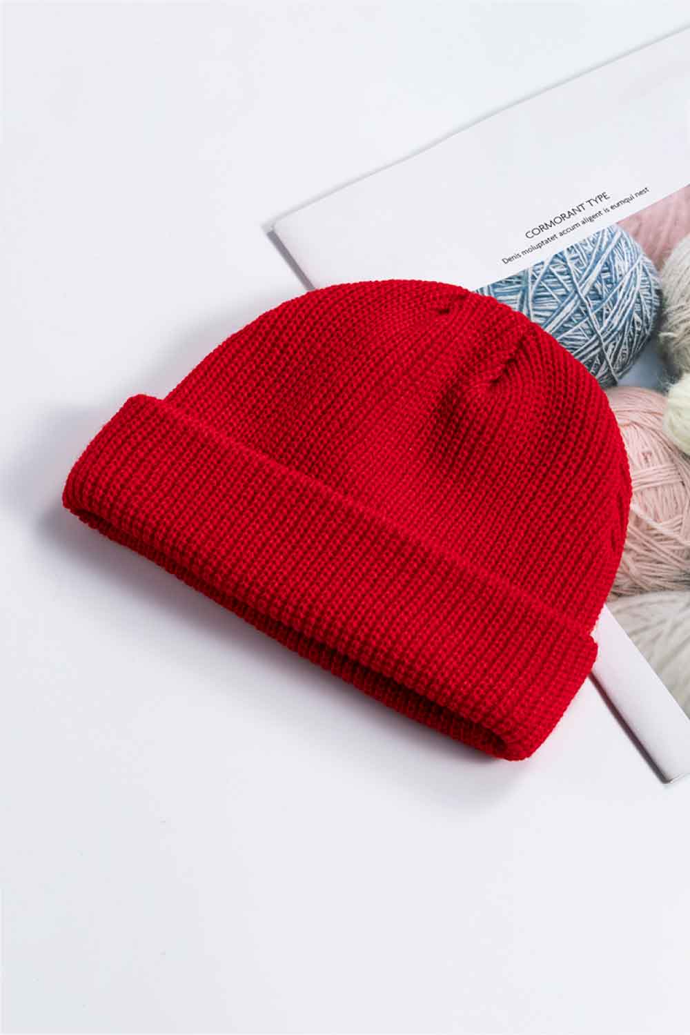 Red knit cuff beanie displayed at an angle on a printed page.
