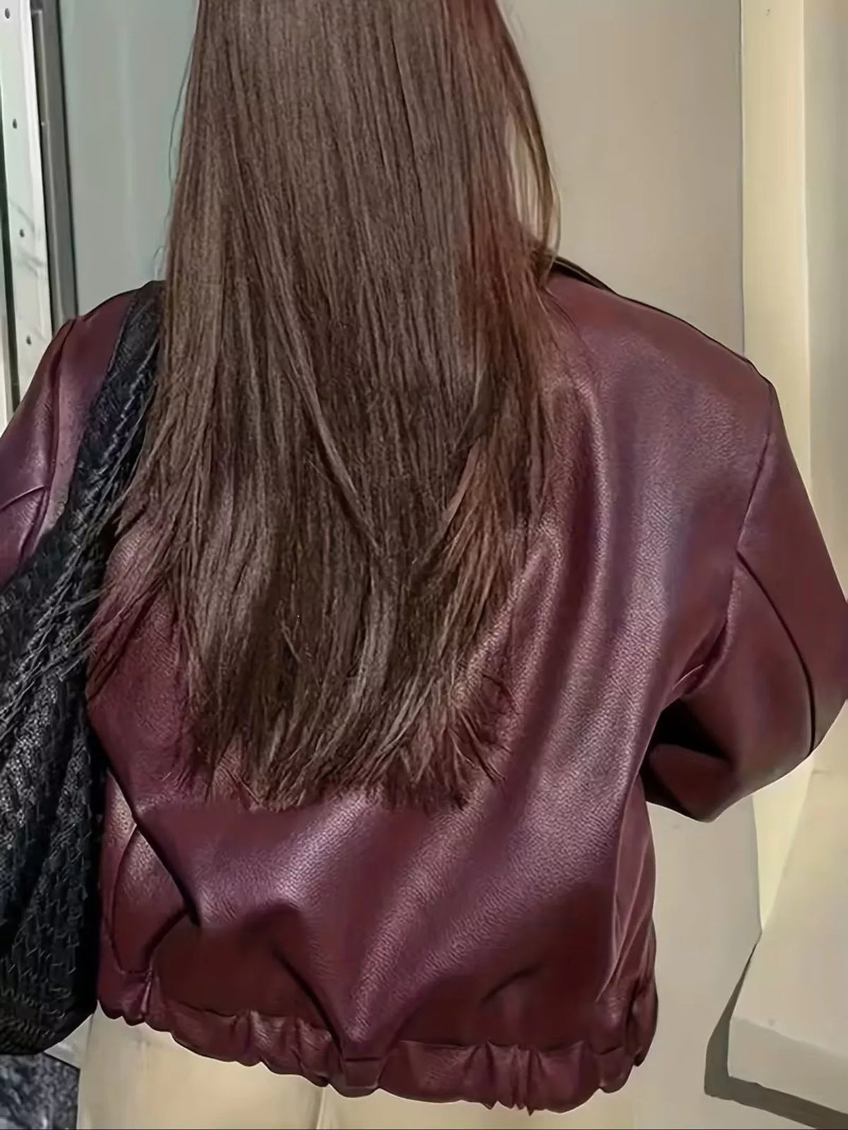 Back view of the burgundy faux leather jacket showing its gathered lower hem.