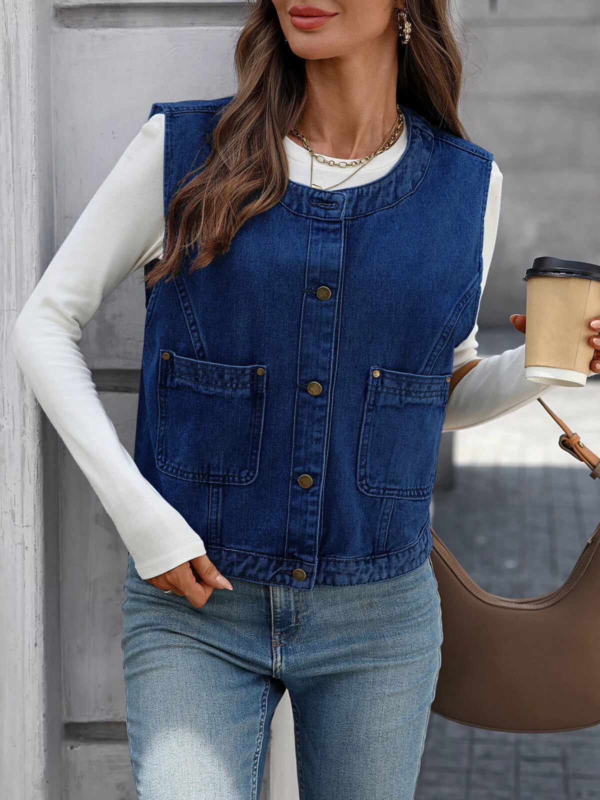 Navy denim-look vest buttoned over a white top, shown with a coffee cup and brown bag.