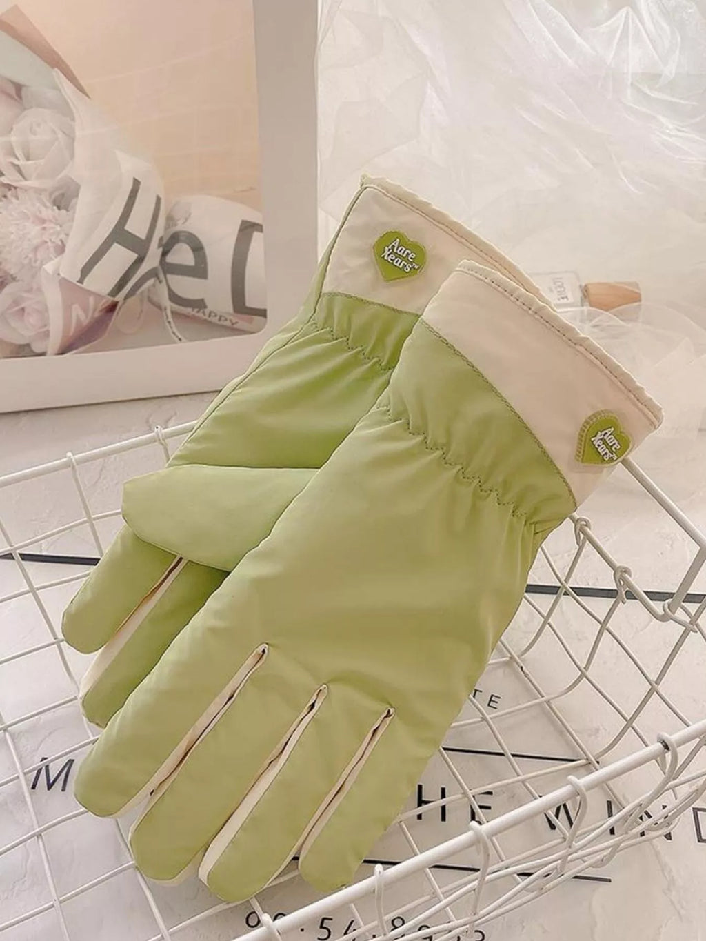 Light green gloves angled on a wire tray, showing the fingers and cream cuffs.