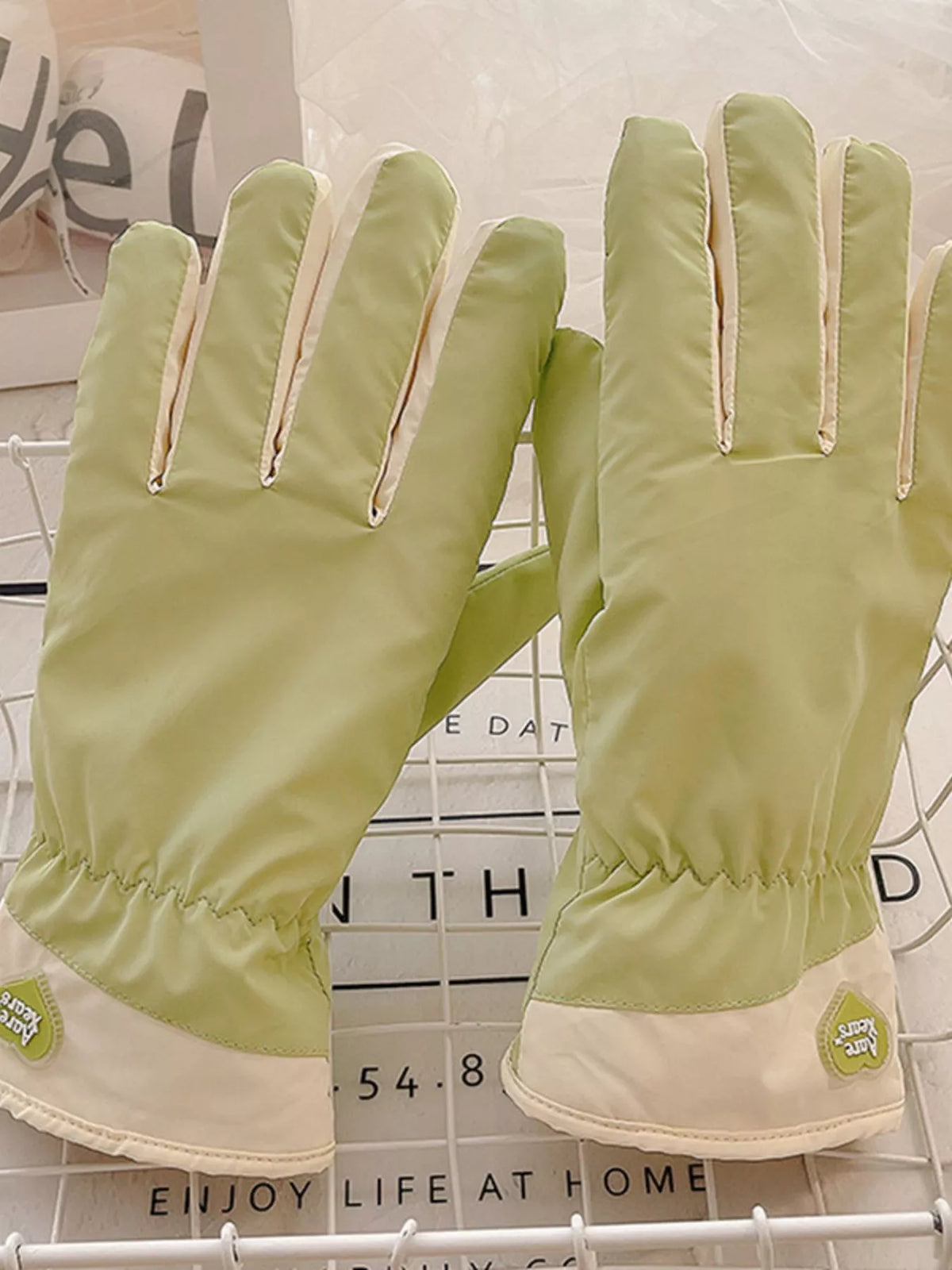 Front view of the light green glove pair with cream trim along the fingers.