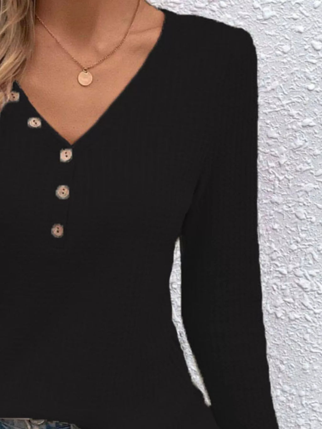 Close view of the Black top showing its V-neck and decorative buttons.