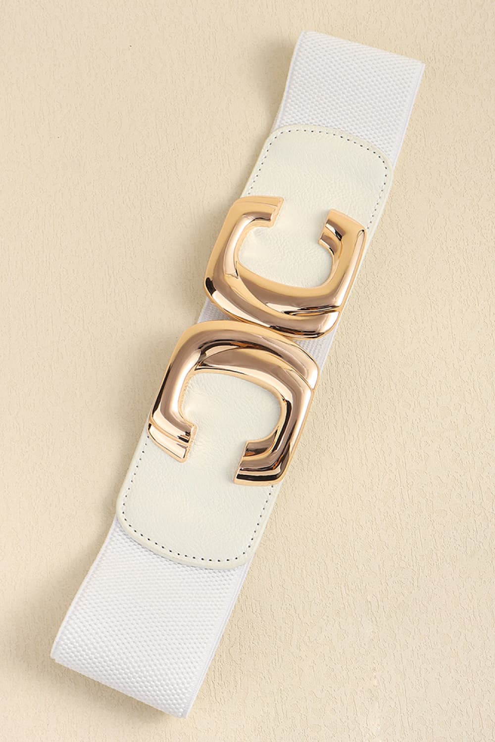 Close-up of the fastened metal buckle on the white waist belt.