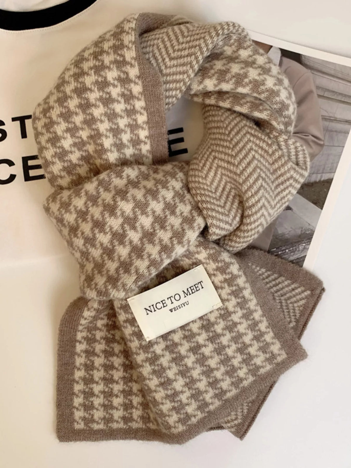 Khaki scarf showing houndstooth and chevron patterns with a decorative fabric label.