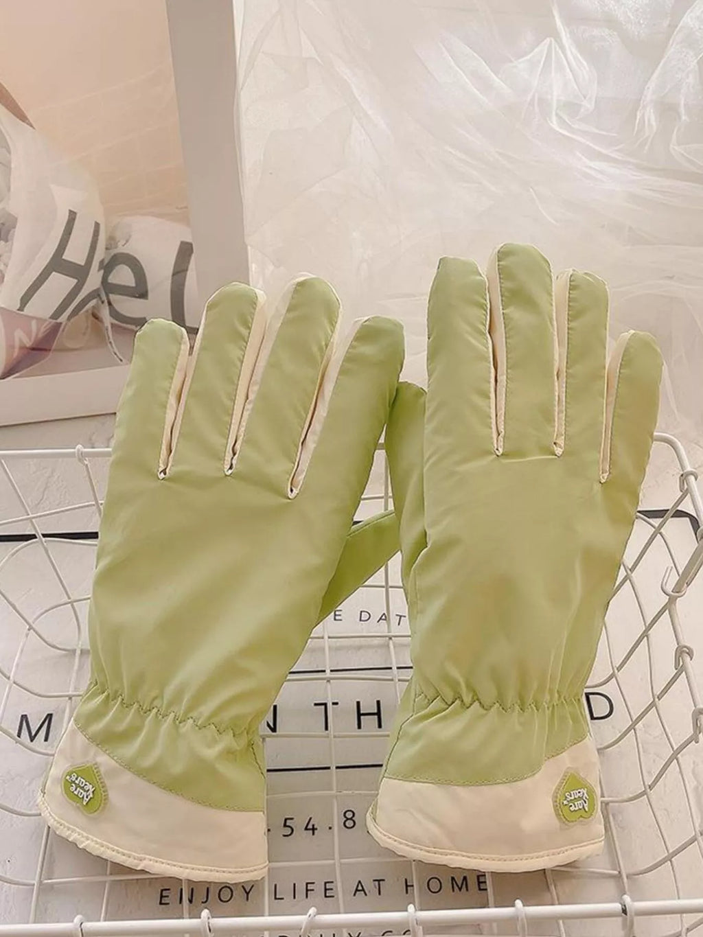 Light green gloves displayed upright side by side on a wire tray.
