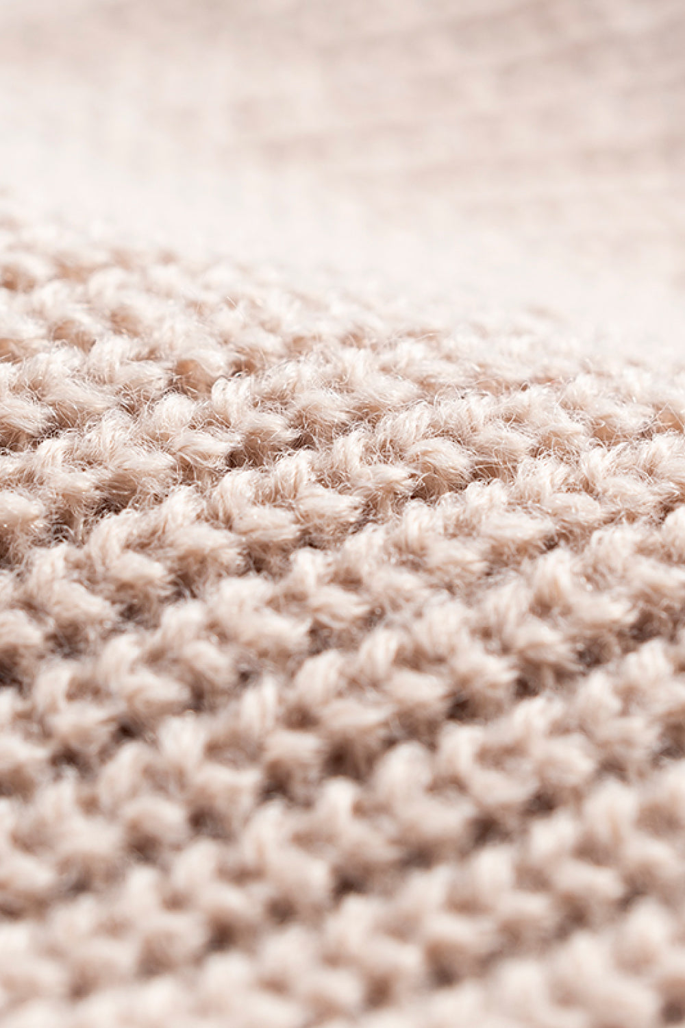 Close-up of the tan beanie's knitted stitch texture.