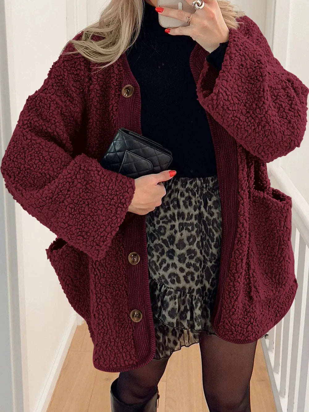 Burgundy textured jacket worn open over a black top and leopard-print skirt.