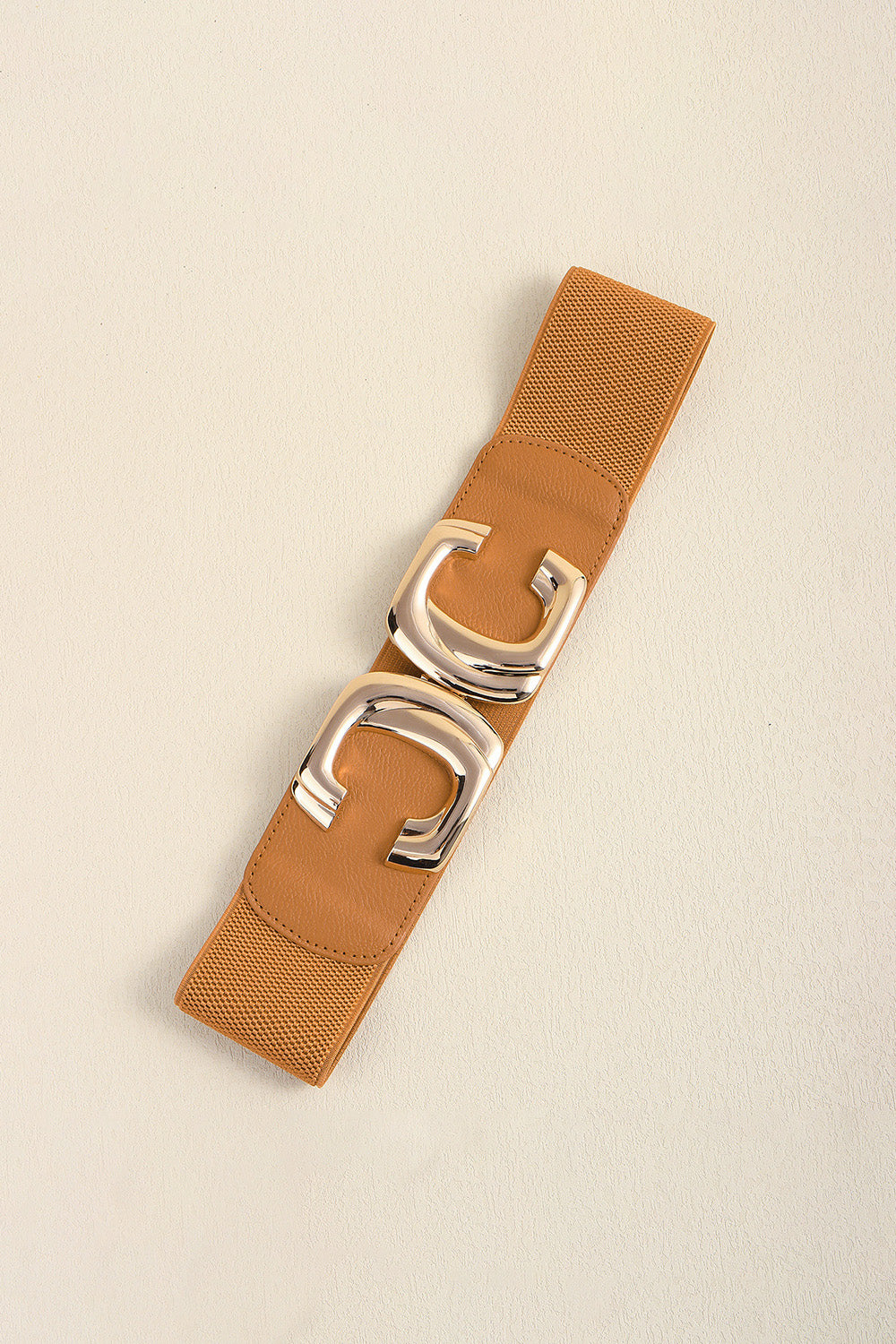 Close-up of the fastened metal buckle on the caramel waist belt.