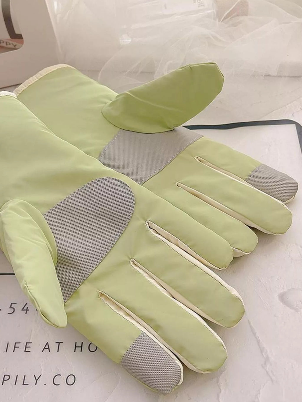 Palm view of light green gloves showing gray textured panels and fingertip patches.