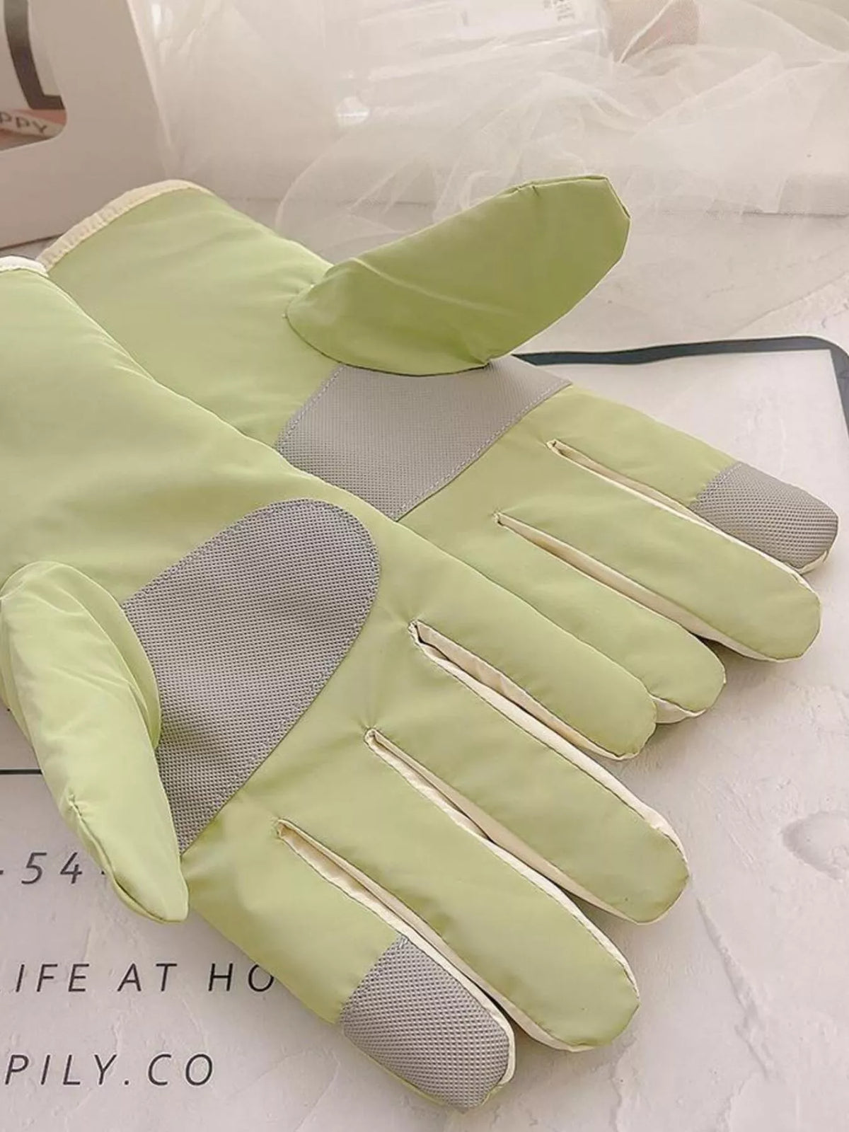 Palm view of light green gloves showing gray textured panels and fingertip patches.