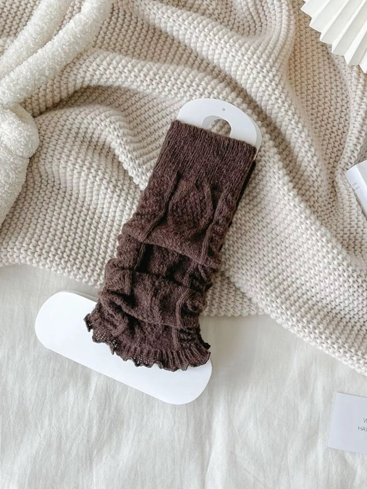 Coffee brown cable-knit leg warmers gathered on a white display card.