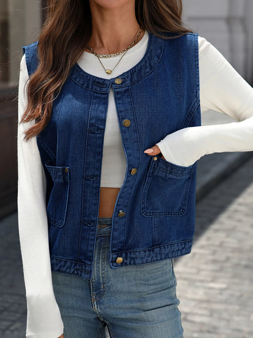 Navy button-front denim-look vest with patch pockets, worn open over a white top.