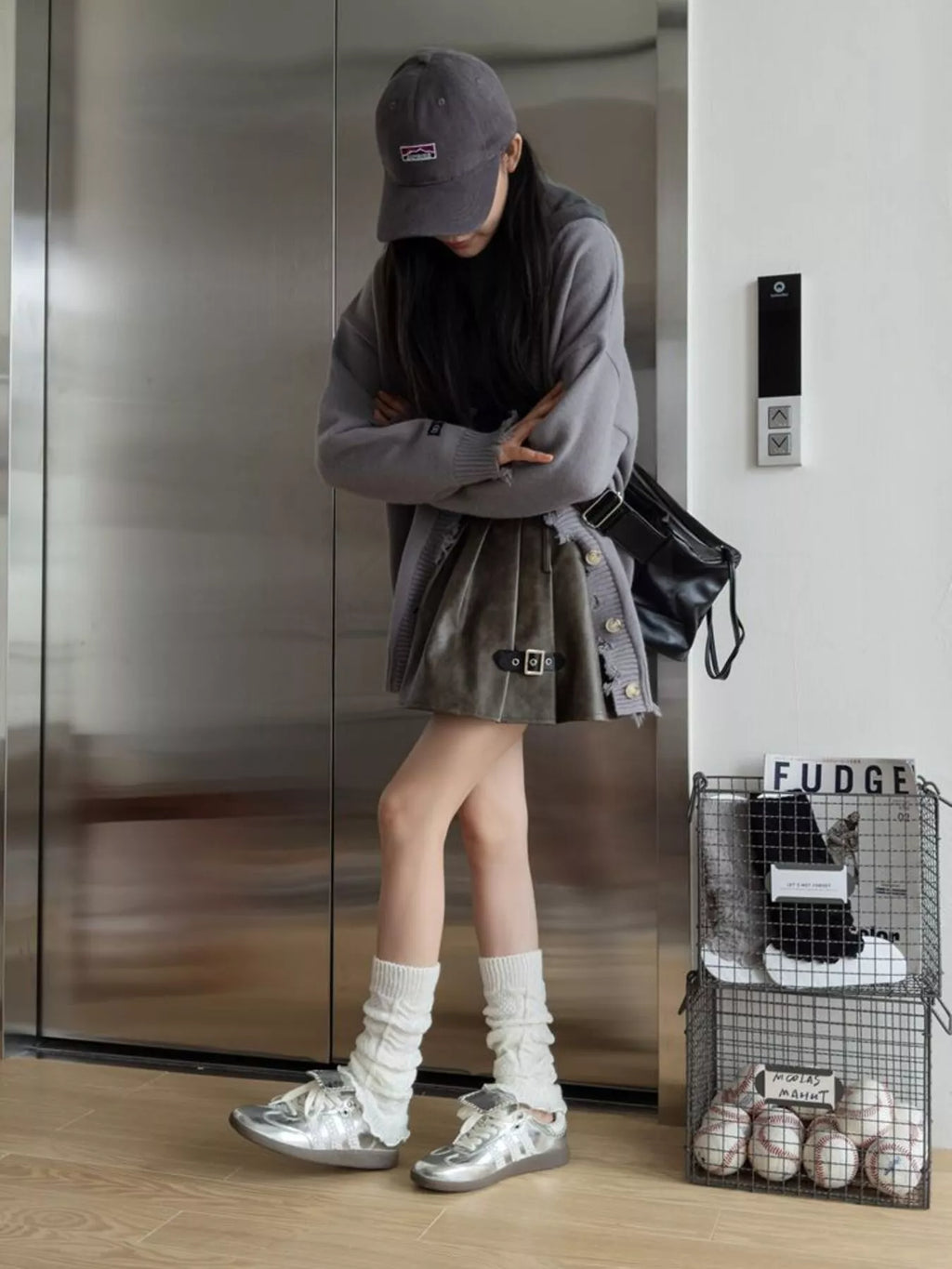 Full outfit view of white leg warmers with silver sneakers and a black skirt.