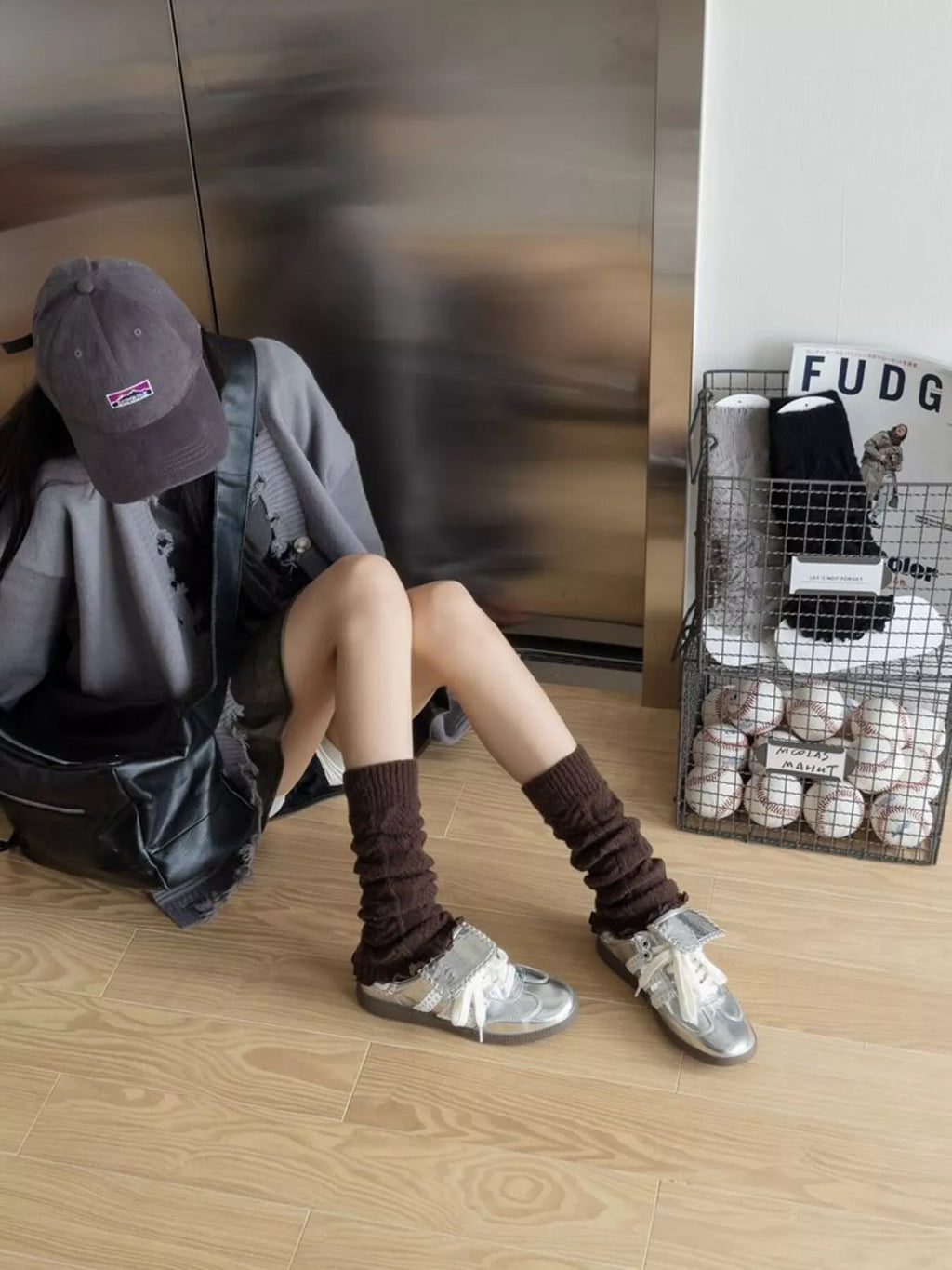 Coffee brown leg warmers worn with silver sneakers by a seated model.