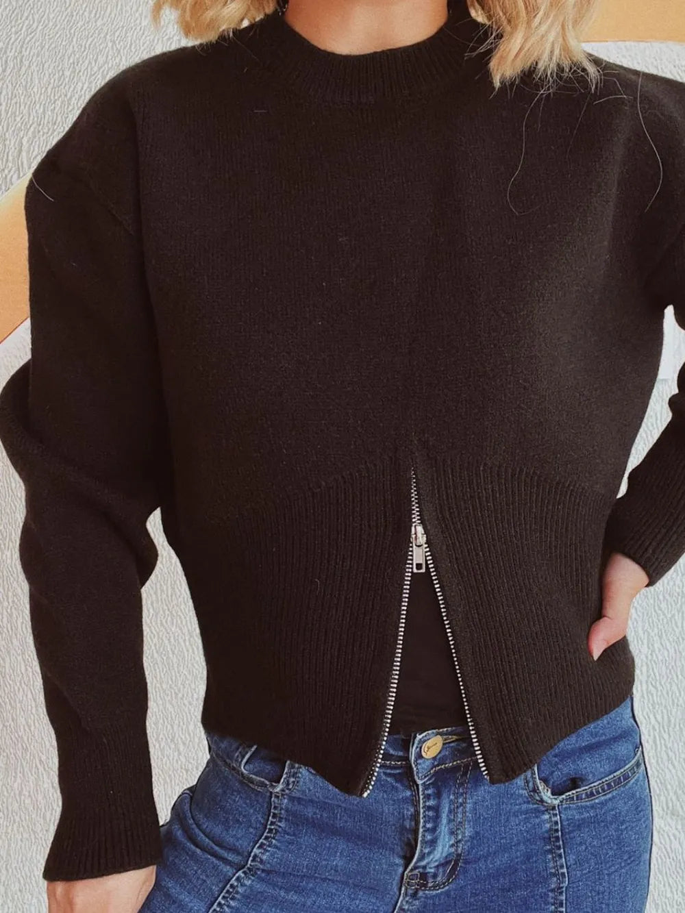 Close view of the Black half-zip knit sweater with the zip open at the hem.